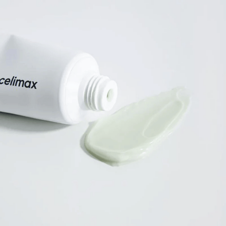 Celimax Noni Energy Repair Cream i en vit tub med en liten mängd ljusgrön kräm utsprutad bredvid tuben på en vit yta. Krämen är för att ge näring och reparera huden.