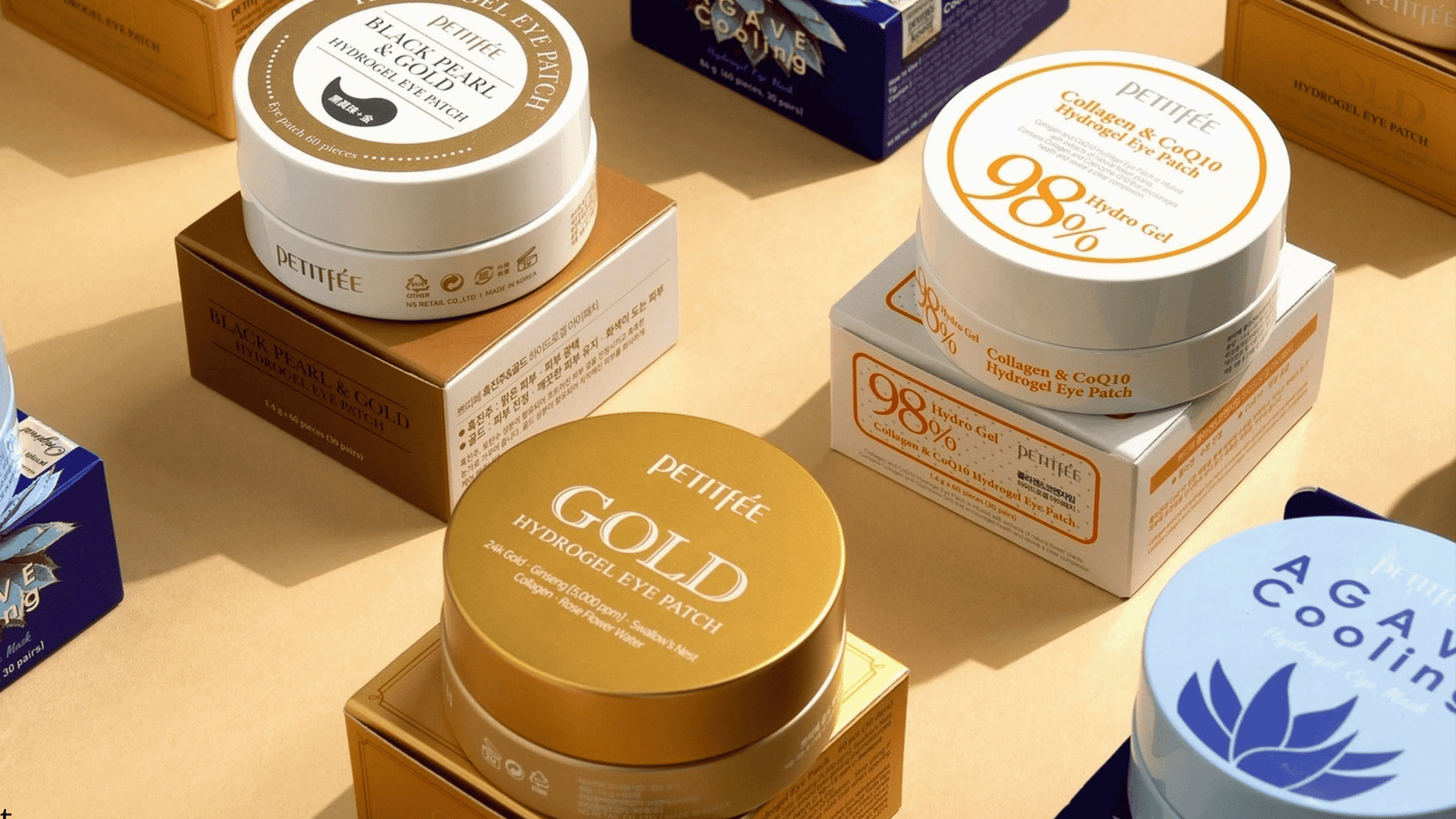 Produktbild med flera hydrogel eye patches från PETITFEE på ljus bakgrund. Förpackningarna i olika färger framhäver varianter som Gold, Black Pearl och Collagen & CoQ10 med fokus på återfuktning och lyster kring ögonen.
