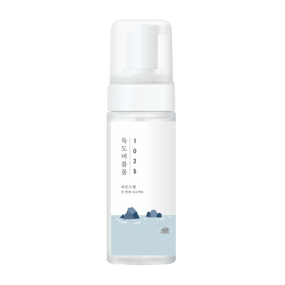 1025 Dokdo Bubble Foam" jest produktem do oczyszczania twarzy od ROUND LAB, zapakowanym w białą butelkę z pompką o prostym i czystym designie, ozdobionym tekstem i minimalistycznymi ilustracjami krajobrazu morskiego. 