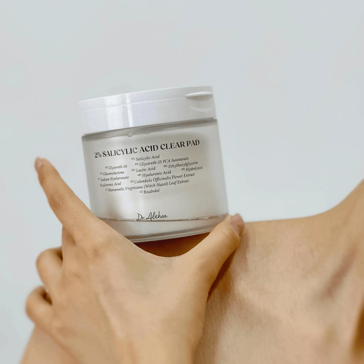 Dr. Althea 2% Salicylic Acid Clear Pad trzymane w ręku. Płatki tonizujące z 2% kwasem salicylowym, które delikatnie eksfoliują, łagodzą skórę i poprawiają jej strukturę.