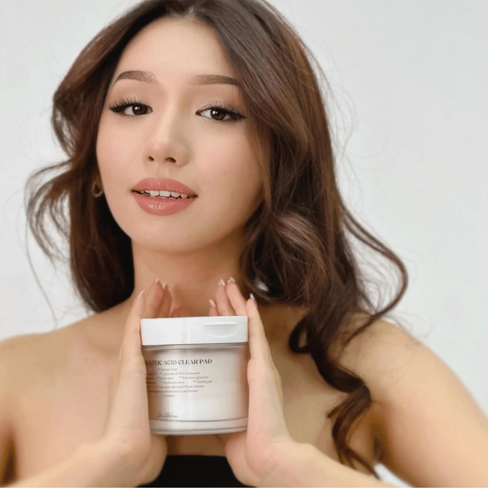 Model trzyma Dr. Althea 2% Salicylic Acid Clear Pad przed twarzą. Eksfoliujące płatki tonizujące z kwasem salicylowym, które oczyszczają pory, równoważą sebum i zapewniają jaśniejszą skórę.