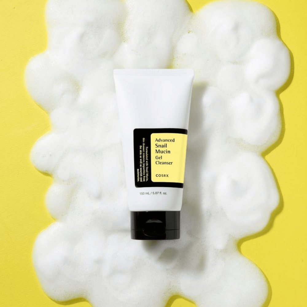 COSRX Advanced Snail Mucin Gel Cleanser 150 ml otoczony obfitą pianą na żółtym tle – delikatne koreańskie oczyszczanie twarzy z krem ze śluzem ślimaka dla nawilżenia i blasku.