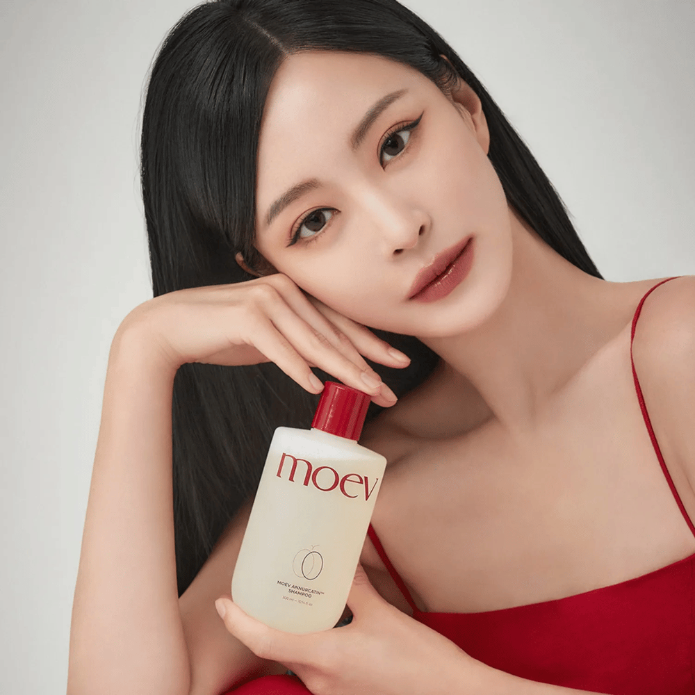 Kobieta z długimi, lśniącymi włosami trzyma MOEV Annurcatin Shampoo – koreański szampon, który nawilża, wzmacnia i chroni włosy dzięki naturalnym składnikom.