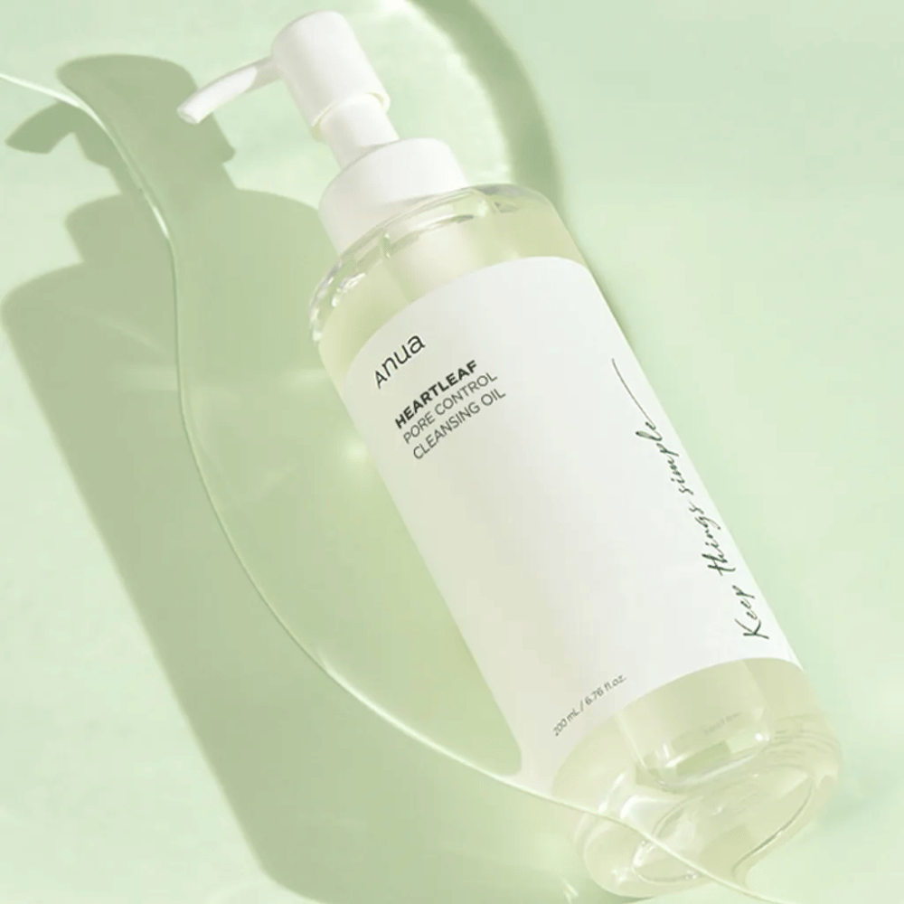 Na zdjęciu widoczny jest ANUA Heartleaf Pore Control Cleansing Oil, olejek oczyszczający z pompką. Butelka jest przezroczysta, a zawartość wygląda na lekką, oleistą konsystencję. Etykieta zawiera logo marki i nazwę produktu w prostym i eleganckim tekście, co przyczynia się do poczucia minimalistycznego piękna i czystości. Na etykiecie widnieje napis "Keep things simple" jako część projektu, co sugeruje filozofię prostoty w rutynie pielęgnacji skóry. Butelka zawiera 200 ml produktu.
