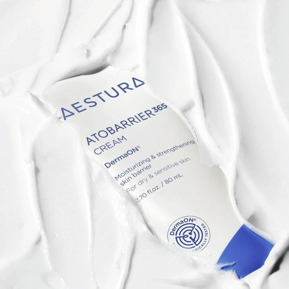 Aestura Atobarrier 365 Cream jest idealny dla suchej i wrażliwej skóry. Dzięki technologii DermaON™, ten krem nawilża i wzmacnia barierę skórną. Produkt jest przedstawiony tutaj w tubie 80 ml, częściowo pokrytej własną kremową konsystencją, co podkreśla jego bogate, nawilżające właściwości.