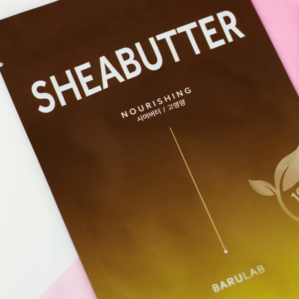 Zbliżenie na opakowanie maski BARULAB "SHEABUTTER Nourishing". Produkt oznaczony jest jako "100% Vegan Product" i ma gradient kolorów od ciemnobrązowego do jasnobrązowego.