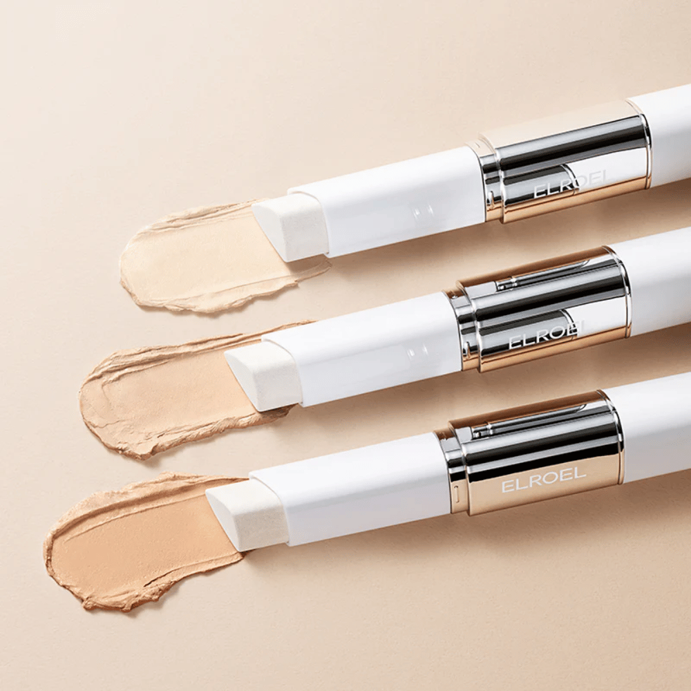 ELROEL Blanc Cover Cream Stick concealer z wbudowanym pędzlem, kilka sztyftów ustawionych w rzędzie pokazujących design produktu i aplikację.