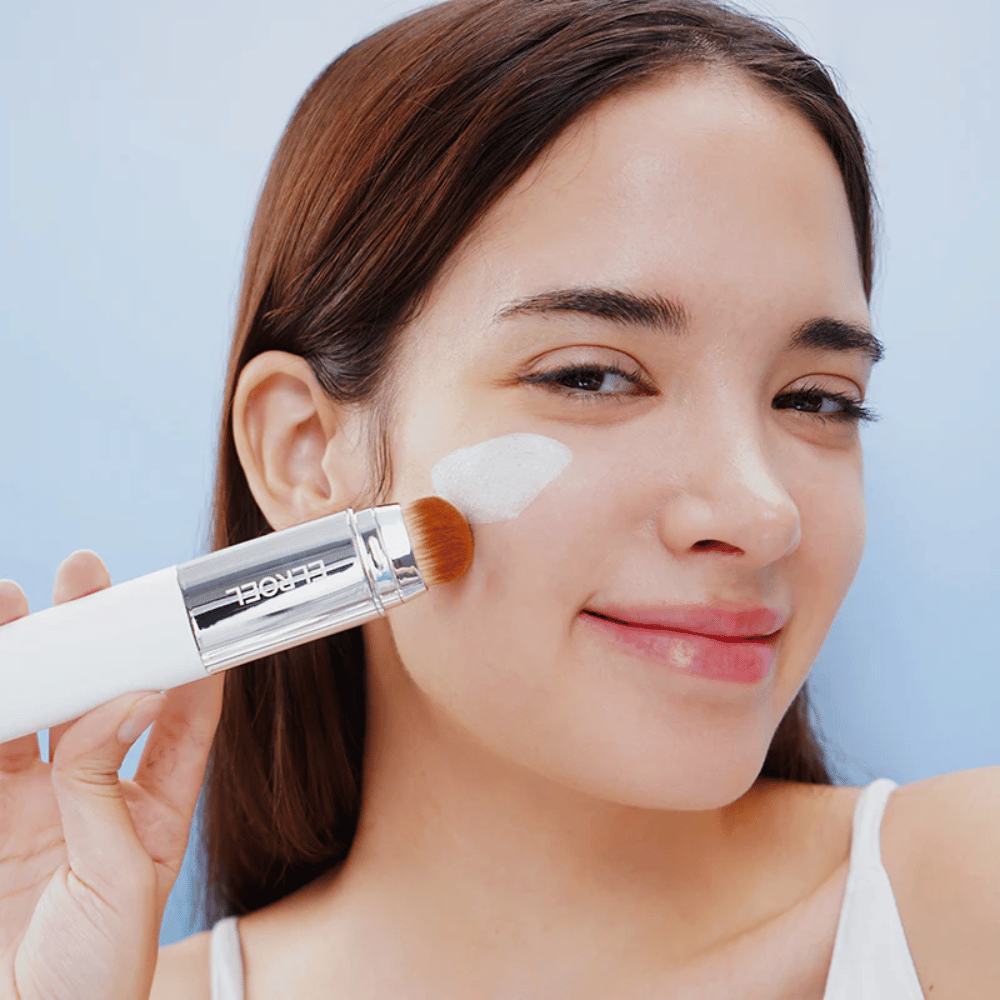 Modelka nakłada ELROEL Blanc Cover Cream Stick concealer na policzek z wbudowanym pędzlem dla naturalnego i jednolitego krycia.