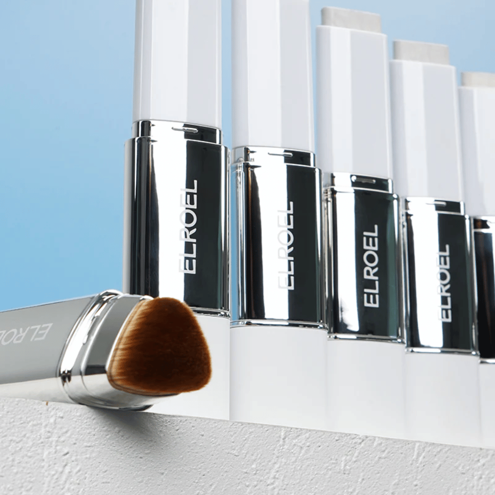 ELROEL Blanc Cover Cream Stick concealer z kilkoma odcieniami nałożonymi jako swatche pokazujące kolor, krycie i kremową konsystencję.