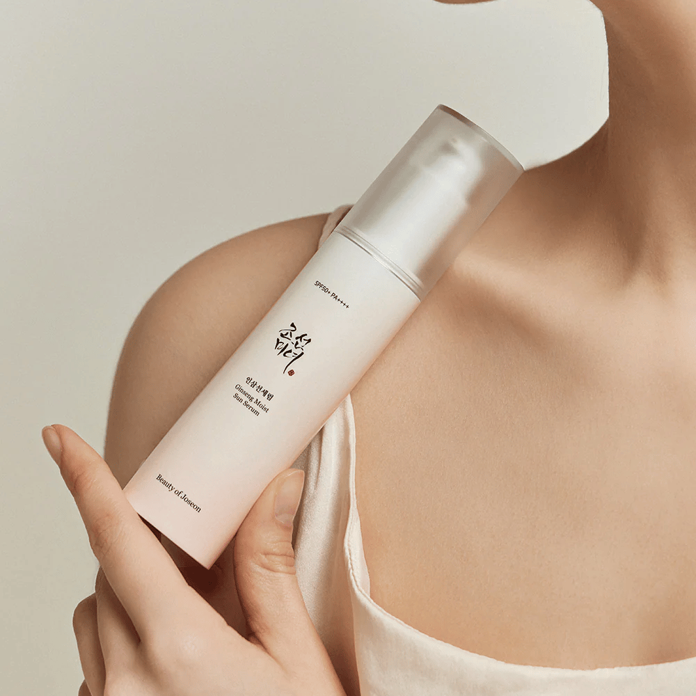 Kobieta trzymająca butelkę Beauty of Joseon's Ginseng Moist Sun Serum SPF 50+ PA++++, która zapewnia SPF 50+ PA++++ ochronę i korzyści dla skóry.