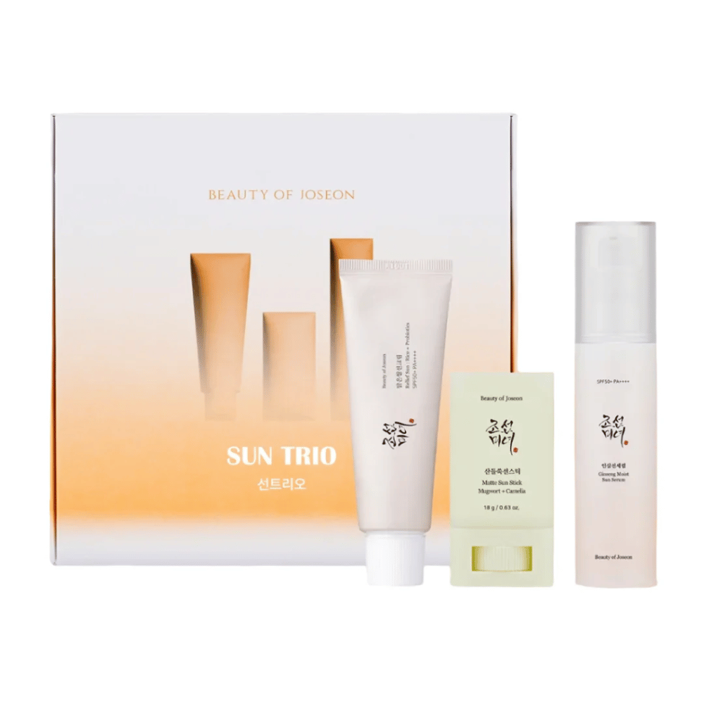 Beauty of Joseon - Sun Trio zestaw prezentowy z trzema produktami do ochrony przeciwsłonecznej: Relief Sun Rice + Probiotics, Matte Sun Stick Mugwort + Camellia i Ginseng Moist Sun Serum na tle gradientowego opakowania w kolorach białym i pomarańczowym.