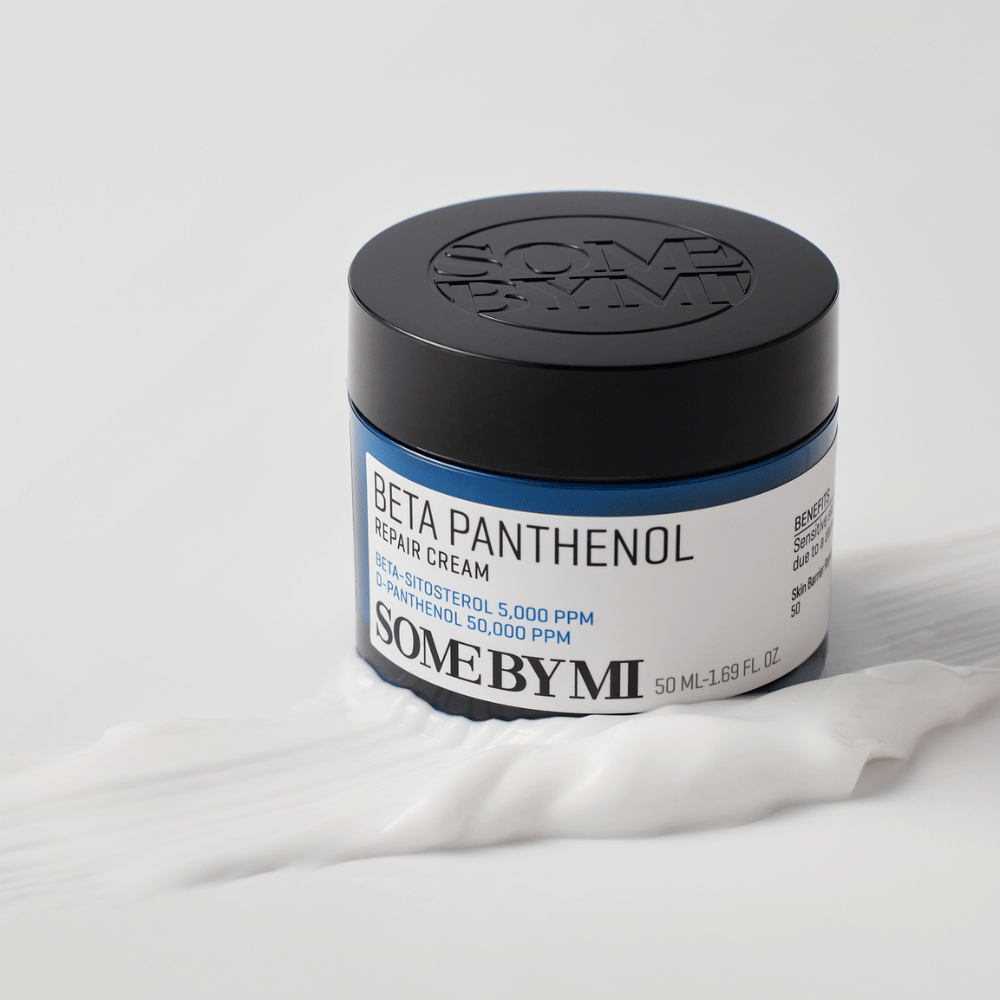SOME BY MI Beta Panthenol Repair Cream w niebieskim słoiku umieszczony na teksturze kremu – łagodzący i nawilżający krem do skóry.