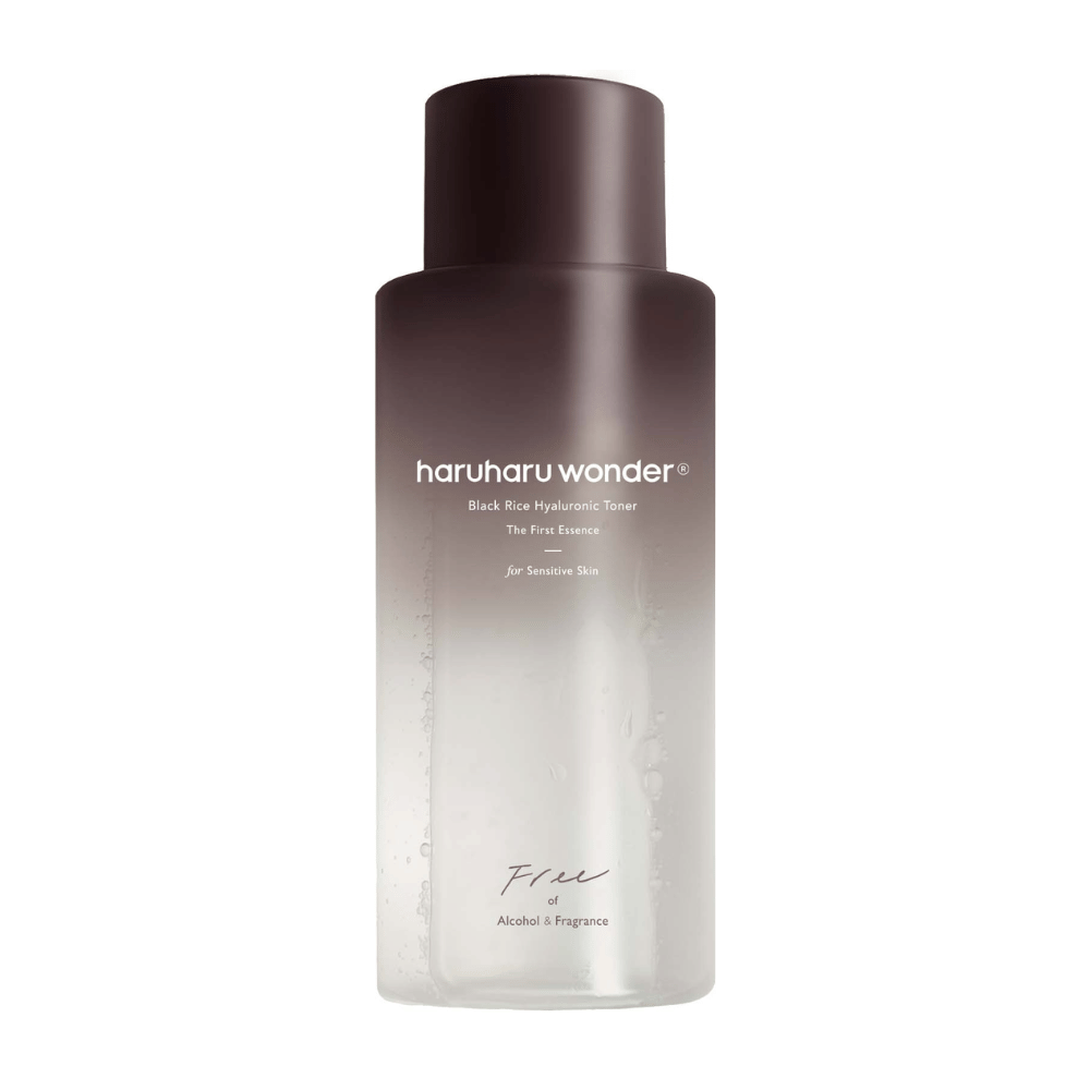 Butelka haruharu wonder Black Rice Hyaluronic Toner The First Essence, z ciemnobrązowym do przezroczystego gradientem i napisem "Free of Alcohol & Fragrance", na białym tle.