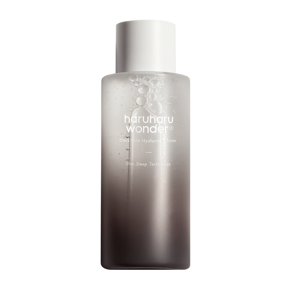 Butelka haruharu wonder Black Rice Hyaluronic Toner z szaro-białym gradientem koloru i kroplami wody na powierzchni, na białym tle.