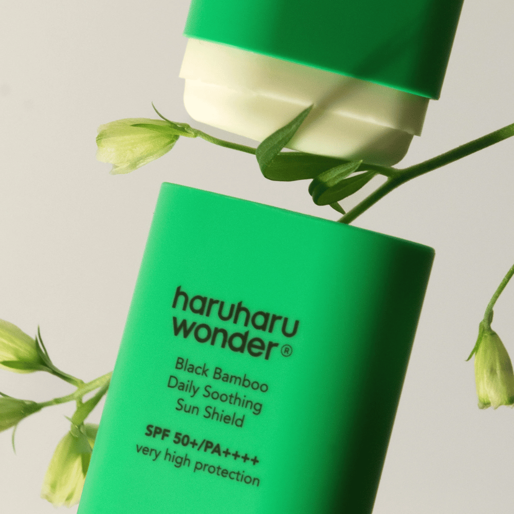 Zbliżenie na Haruharu Wonder Black Bamboo Daily Soothing Sun Shield – zielony sztyft przeciwsłoneczny z SPF 50+ PA++++, otoczony zielonymi detalami roślinnymi.