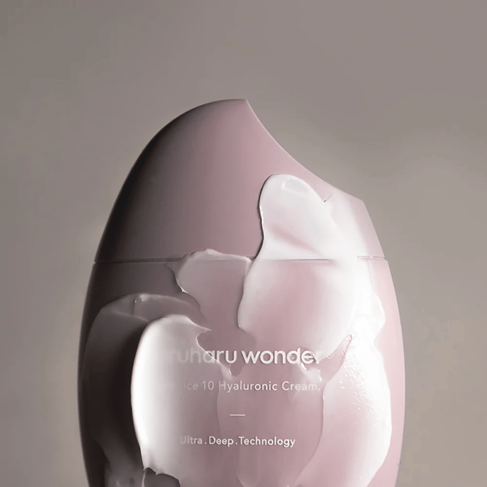 Obraz przedstawia słoik z "Haruharu Wonder Black Rice 10 Hyaluronic Cream", który jest częściowo pokryty grubym, przezroczystym kremem. Tekst na obrazie sugeruje użycie zaawansowanej technologii do głębokiego nawilżania skóry. Design jest nowoczesny i minimalistyczny.