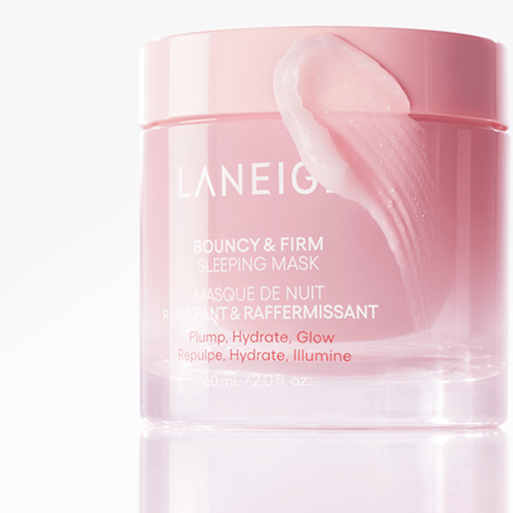 Zbliżenie na Laneige Bouncy & Firm Sleeping Mask w różowym słoiku, z częścią maski nałożoną na krawędź pokrywki. Produkt jest przeznaczony do zapewnienia wypełnienia, nawilżenia i blasku. Słoik mieści 60 ml i ma tekst "Plump, Hydrate, Glow."