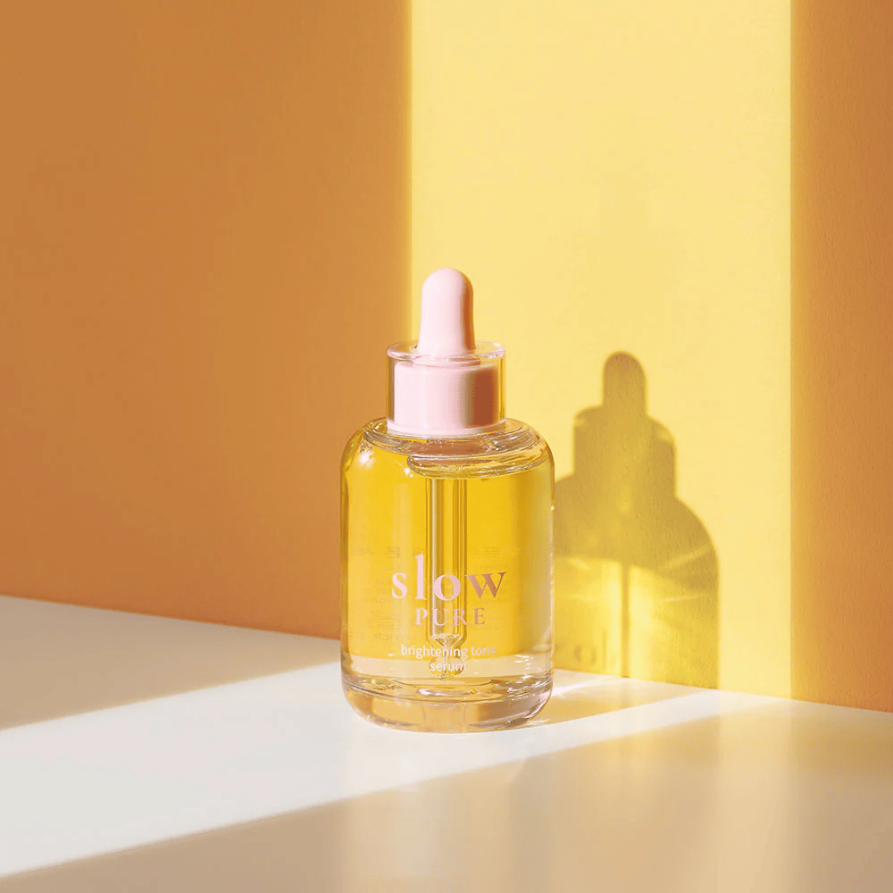 Slow Pure Brightening Tone Serum w słonecznym żółtym świetle, symbolizuje blask i energię dla skóry.