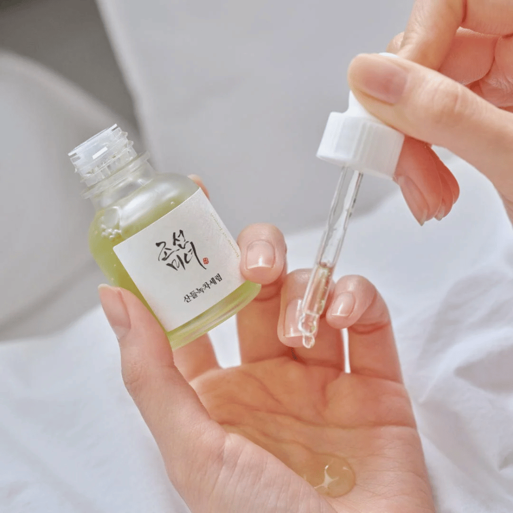 Ręka nakłada Beauty of Joseon Calming Serum Green Tea + Panthenol na skórę – kojące koreańskie serum dla cera wrażliwa.