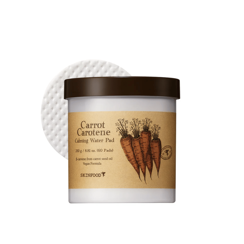 Słoik "Carrot Carotene Calming Water Pad" od SKINFOOD. Słoik zawiera 60 płatków i jest oznaczony obrazkiem marchewek. Produkt, oparty na oleju z nasion marchwi, jest przyjazny dla wegan i zaprojektowany, aby łagodzić skórę.