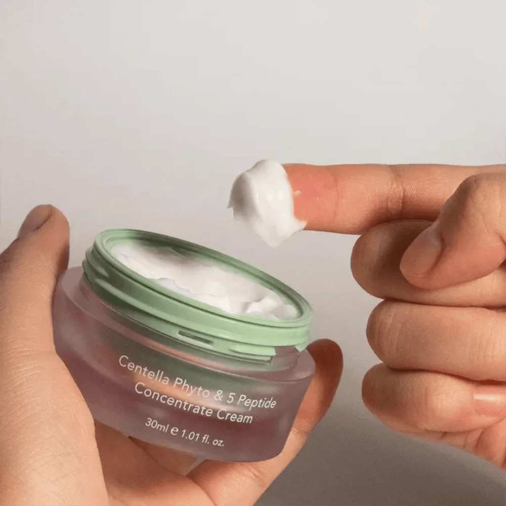 Ręka biorąca porcję Centella Phyto & 5 Peptide Concentrate Cream ze słoika.