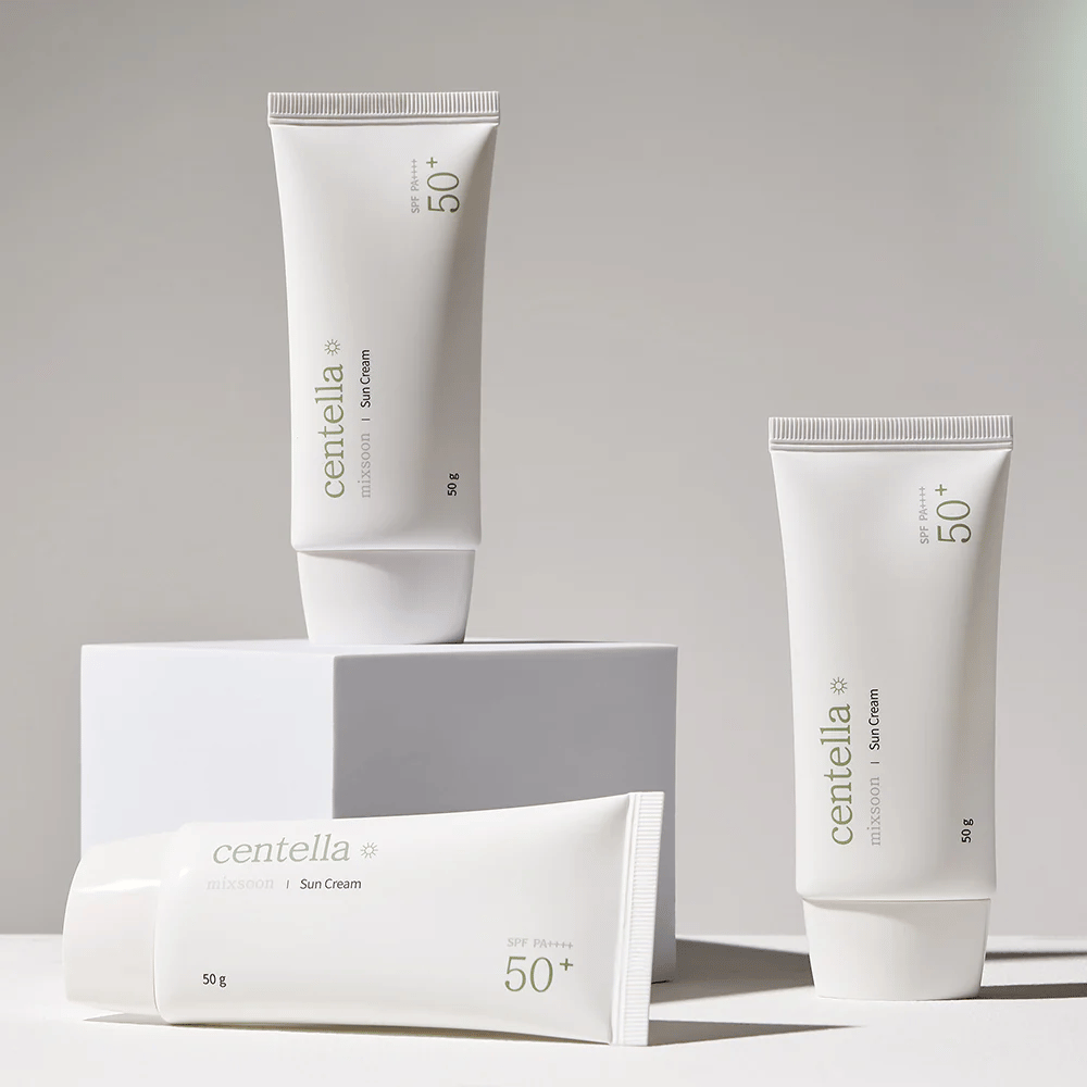 Trzy opakowania Centella Sun Cream SPF 50+ PA++++ estetycznie ułożone na białych podestach. Dwie tubki stoją, a jedna leży, wszystkie z białym, minimalistycznym designem i zielonymi detalami tekstowymi.