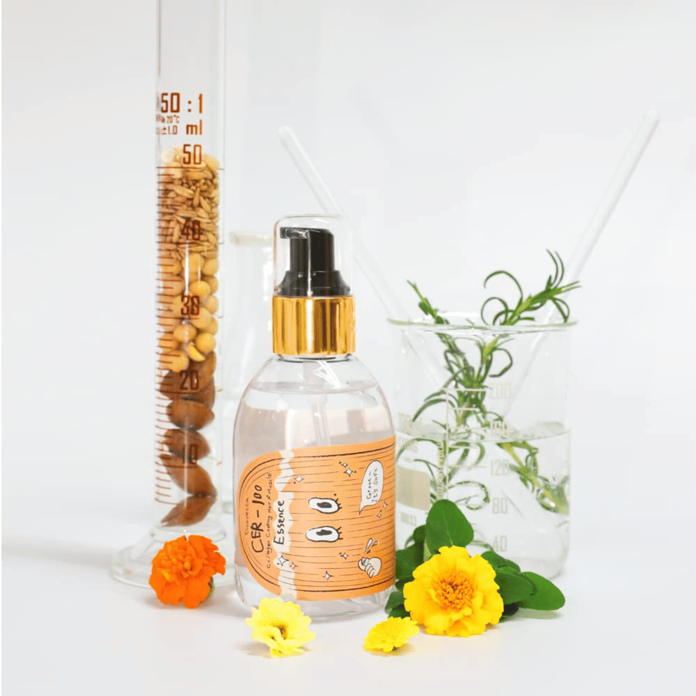 CER-100 Hair Essence wraz z kwiatami i szkłem laboratoryjnym, które podkreślają składniki i pielęgnację włosów.