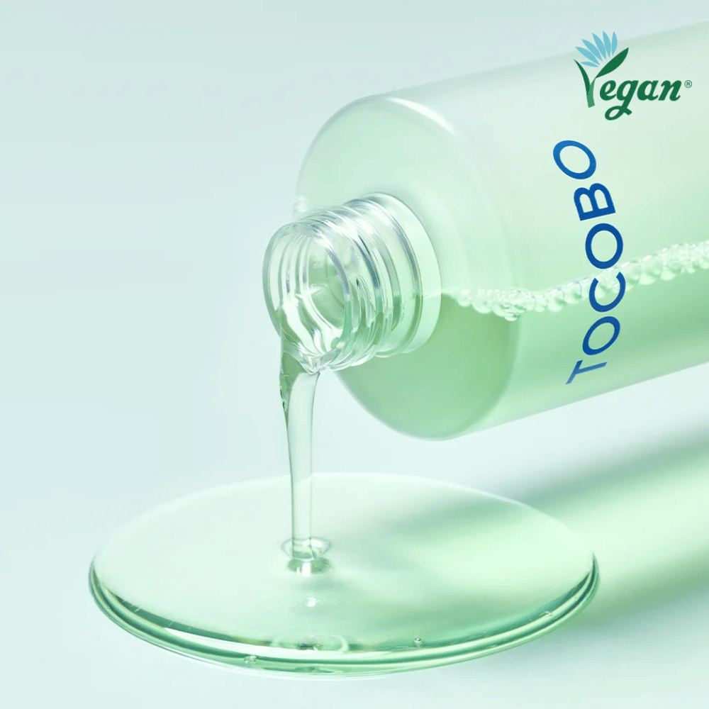 Zbliżenie TOCOBO Cica Calming Aqua Toner, który jest wylewany, aby podkreślić przejrzystą, lekką i chłodzącą konsystencję produktu.