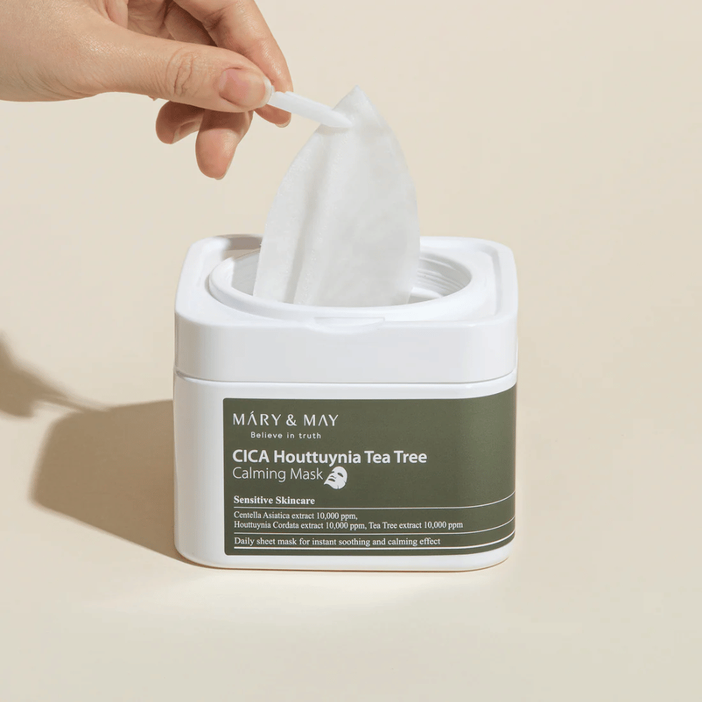 Ręka wyciągająca maseczkę w płachcie ze słoika Mary & May Cica Houttuynia Tea Tree Calming Mask – kojąca maseczka do twarzy dla skóry wrażliwej z Cica i ekstraktem Tea Tree.