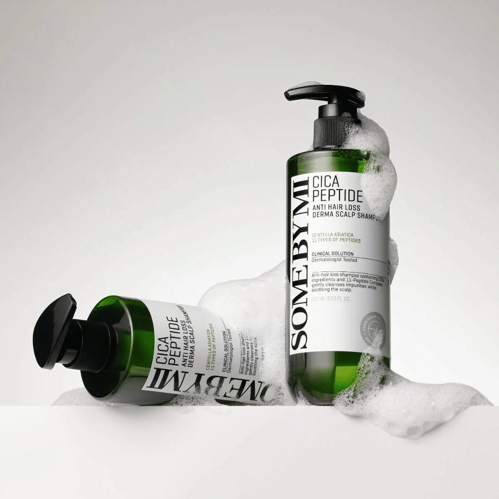 Dwie butelki SOME BY MI Cica Peptide Anti Hair Loss Derma Scalp Shampoo pokryte pianą, stojące i leżące na białym tle.