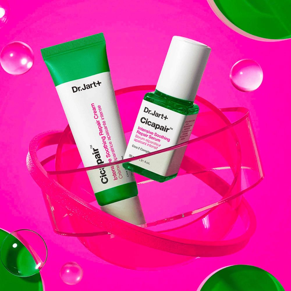 Dr.Jart+ Cicapair Intensive Soothing Repair Cream i Serum w zielonych opakowaniach, stojące na różowej okrągłej podstawie. Produkty zostały stworzone, aby łagodzić i naprawiać podrażnioną skórę.