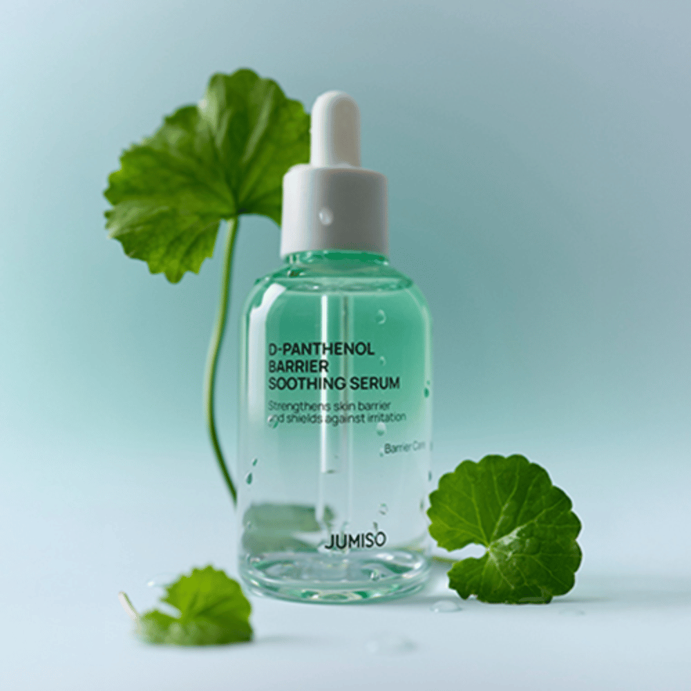 Jumiso D-Panthenol Barrier Soothing Serum w przezroczystej szklanej butelce z pipetą, umieszczona z zielonymi liśćmi w tle.