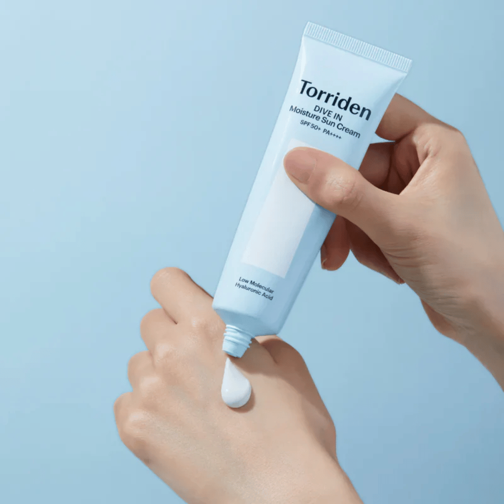 Torriden DIVE-IN Moisture Sun Cream SPF50+ PA++++ nakładany na dłoń, aby pokazać lekką i kremową konsystencję nawilżającego kremu przeciwsłonecznego.