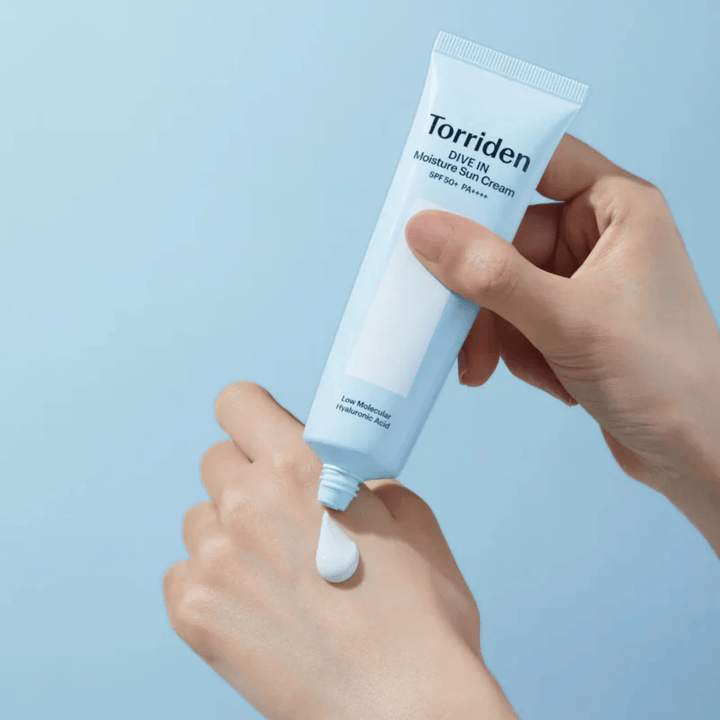 Torriden DIVE-IN Moisture Sun Cream SPF50+ PA++++ nakładany na dłoń, aby pokazać lekką i kremową konsystencję nawilżającego kremu przeciwsłonecznego.