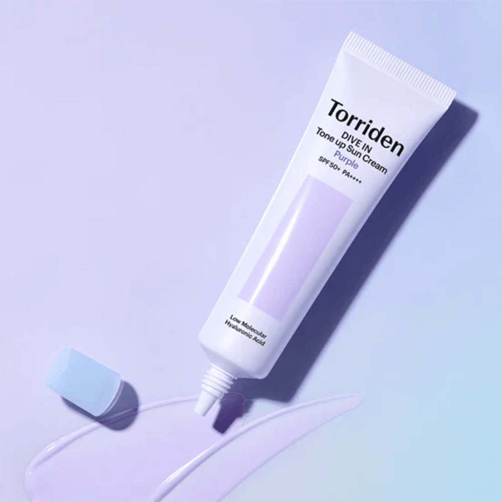 Otwarta tubka Torriden DIVE IN Tone Up Sun Cream Purple z fioletowo zabarwioną konsystencją kremu przeciwsłonecznego, pokazującą korygującą kolor formułę produktu.