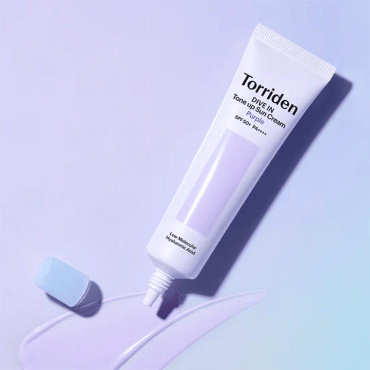 Otwarta tubka Torriden DIVE IN Tone Up Sun Cream Purple z fioletowo zabarwioną konsystencją kremu przeciwsłonecznego, pokazującą korygującą kolor formułę produktu.