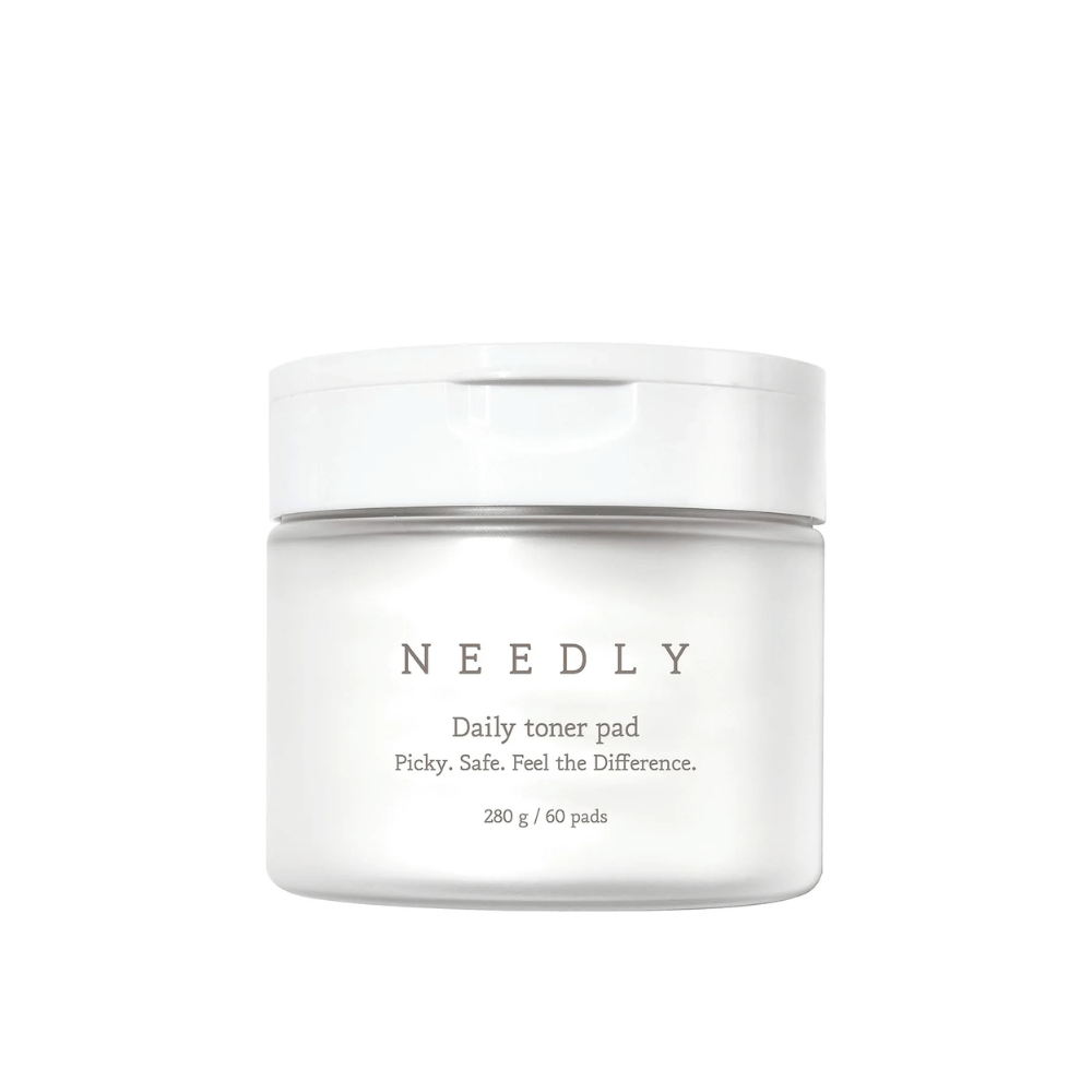 Biały pojemnik z Needly Daily Toner Pad. Opakowanie ma minimalistyczny tekst opisujący produkt i zawiera 280 g, co odpowiada 60 tonikom. Tekst brzmi 'Picky. Safe. Feel the Difference.