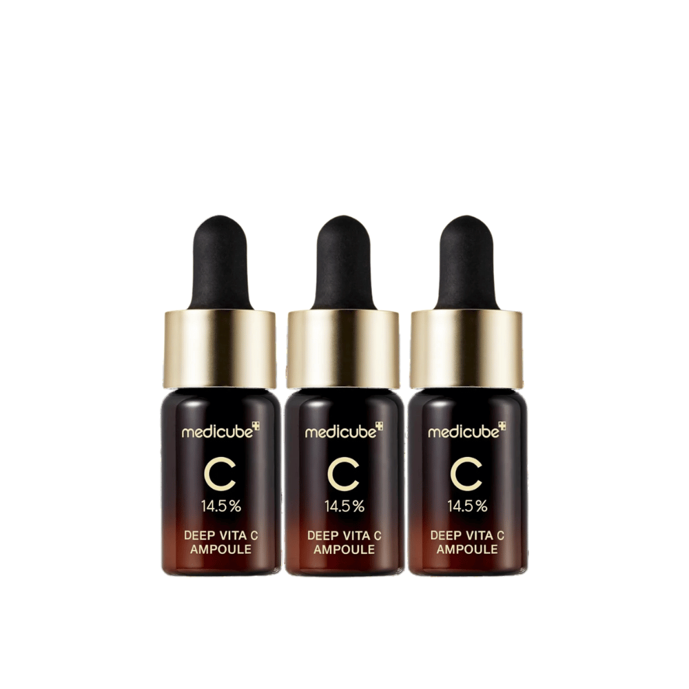 Trzy butelki Medicube Deep Vita C Ampoule, z 14,5% witaminą C, ułożone w rzędzie. Butelki mają elegancki design z ciemnobrązową podstawą i złotym korkiem. Idealne dla jaśniejszego odcienia skóry i bardziej jednolitej tekstury skóry.