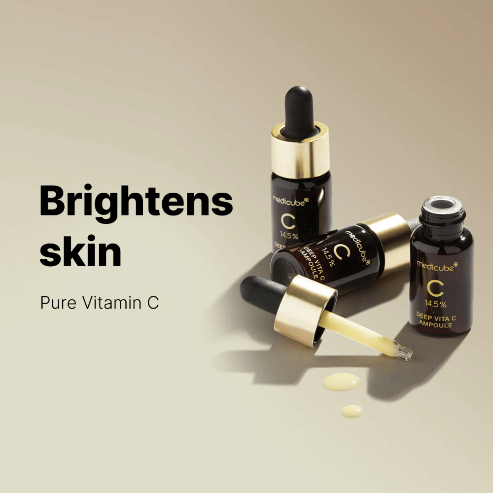 Medicube Deep Vita C Ampoule z 14,5% witaminą C, prezentowane w eleganckich butelkach ze złotymi pipetami. Produkt został zaprojektowany, aby rozjaśniać odcień skóry i nadawać jej promienny wygląd. Tekst "Brightens skin" i "Pure Vitamin C" wzmacnia przekaz.