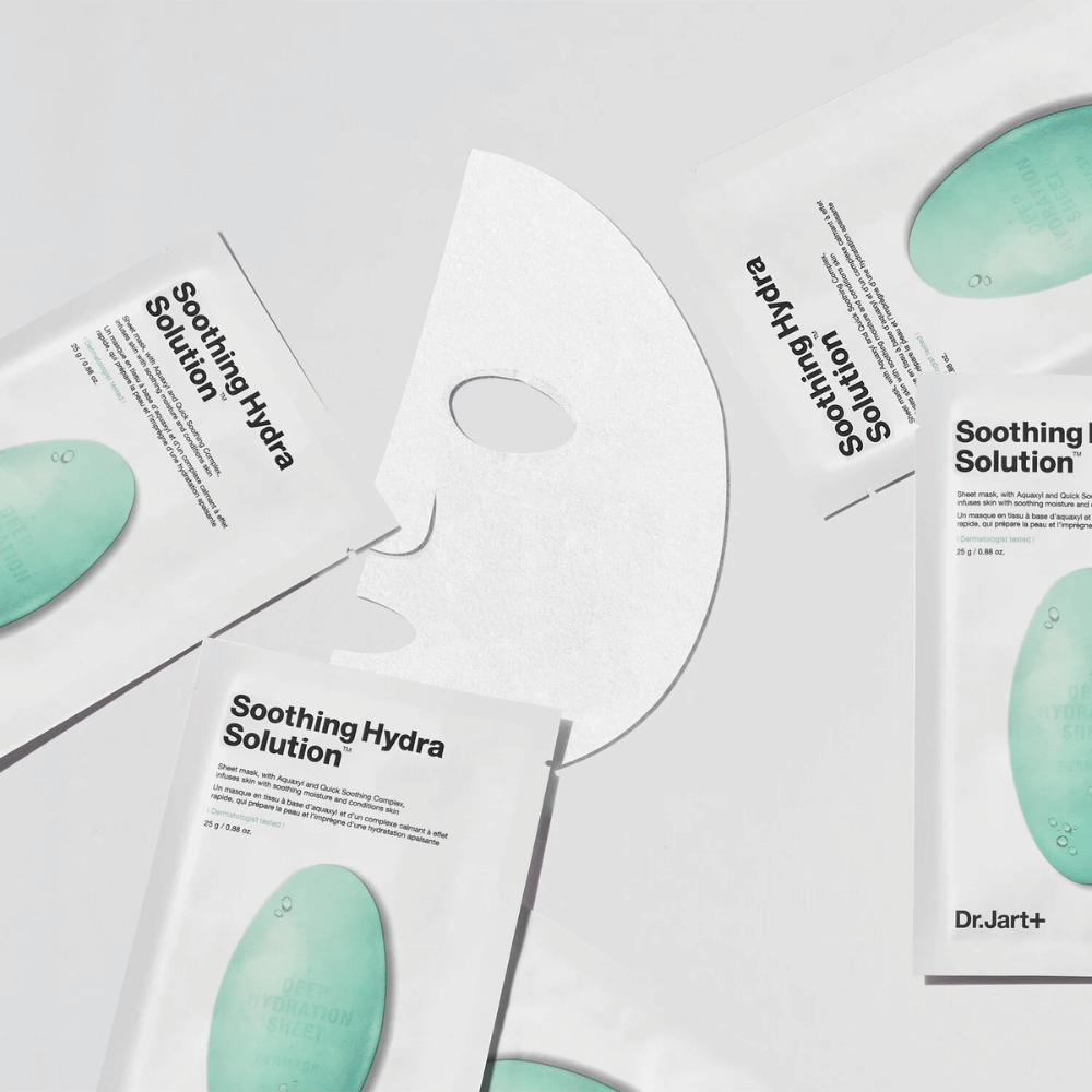 Wiele opakowań maseczek "Soothing Hydra Solution" od Dr.Jart+ jest rozłożonych na jasnej powierzchni. Rozwinięta maseczka umieszczona jest w środku, ukazując swoją białą i perforowaną strukturę.