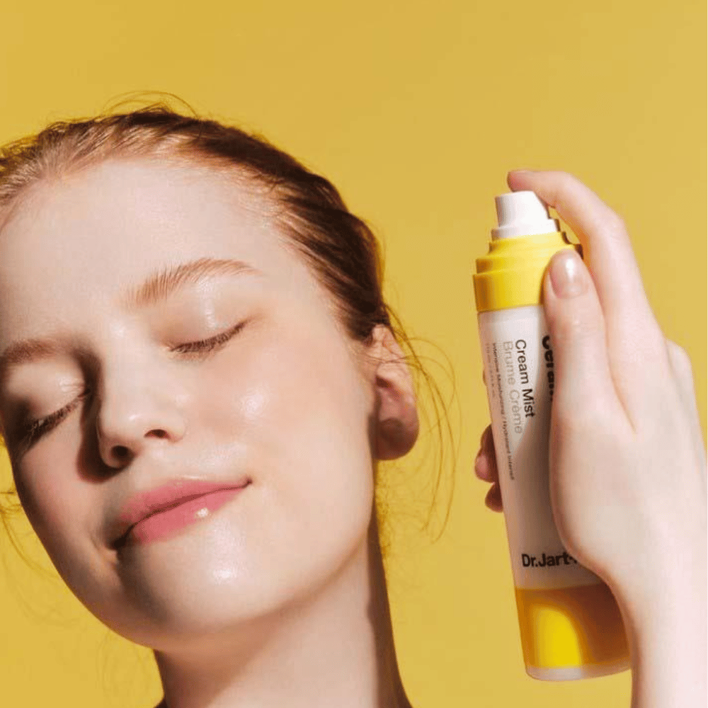 Kobieta trzyma butelkę Dr. Jart+ Ceramidin Cream Mist 110ml przy twarzy, co promuje jej zalety nawilżające i wegańską formułę.