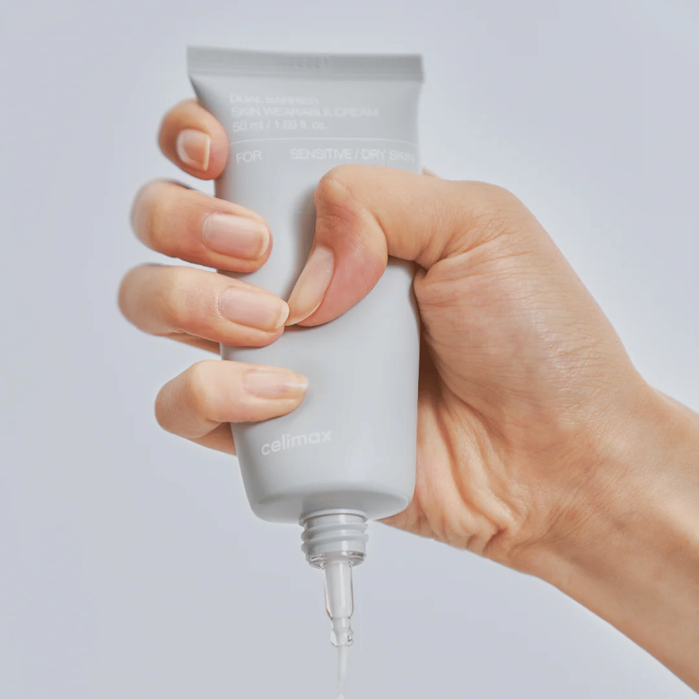 Ręka nakładająca Celimax Dual Barrier Skin Wearable Cream, krem do twarzy wzmacniający barierę, dla skóry wrażliwej i suchej, który zapewnia długotrwałe nawilżenie i chroni barierę skórną.