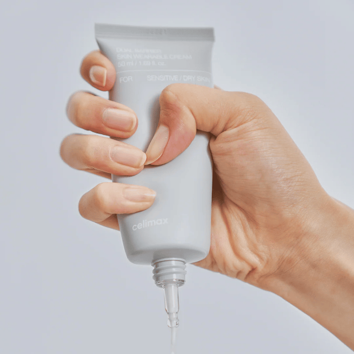 Ręka nakładająca Celimax Dual Barrier Skin Wearable Cream, krem do twarzy wzmacniający barierę, dla skóry wrażliwej i suchej, który zapewnia długotrwałe nawilżenie i chroni barierę skórną.