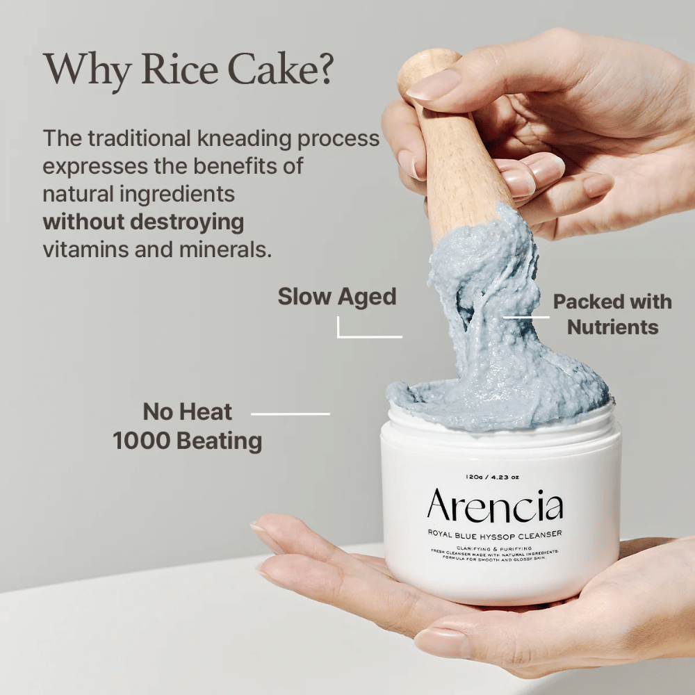 Ręka trzymająca słoik z czyszczącym "Arencia Royal Blue Hyssop Cleanser" z drewnianą łyżką podnoszącą niebieską, mochi-podobną pastę czyszczącą. Tekst na zdjęciu opisuje zalety procesu ciasta ryżowego, takie jak "Bez ciepła", "1000 uderzeń", "Powoli dojrzewające" i "Pełne składników odżywczych".