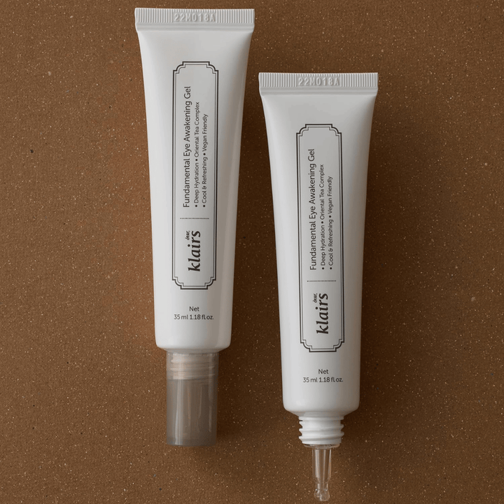 Zdjęcie produktowe przedstawiające Klairs Fundamental Eye Awakening Gel w dwóch wersjach – zamkniętą tubkę oraz otwartą tubkę podkreślającą wąską końcówkę aplikatora. Opakowanie ma minimalistyczny biały design i eksponuje nacisk produktu na nawilżenie, chłodzące uczucie oraz odświeżającą pielęgnację okolic oczu.
