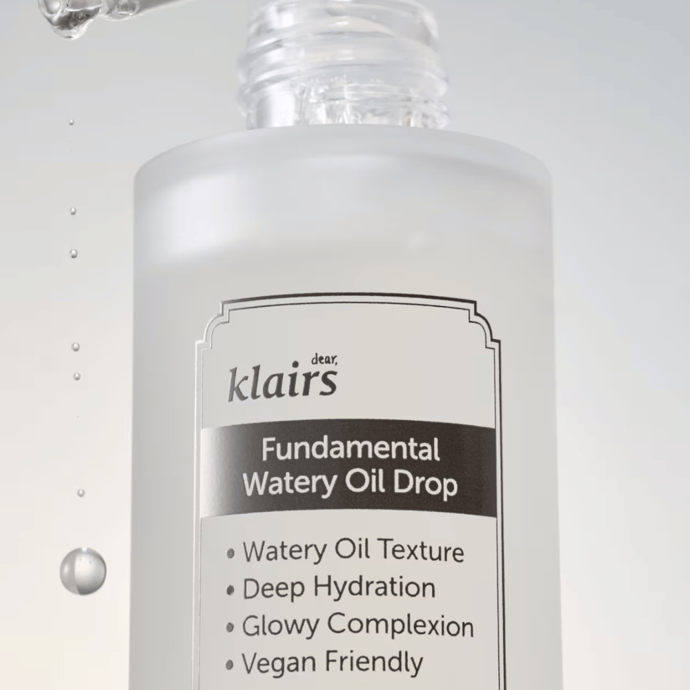Zbliżenie na butelkę Klairs Fundamental Watery Oil Drop, z tekstem podkreślającym właściwości produktu, takie jak "Watery Oil Texture", "Deep Hydration", "Glowy Complexion" i "Vegan Friendly".
