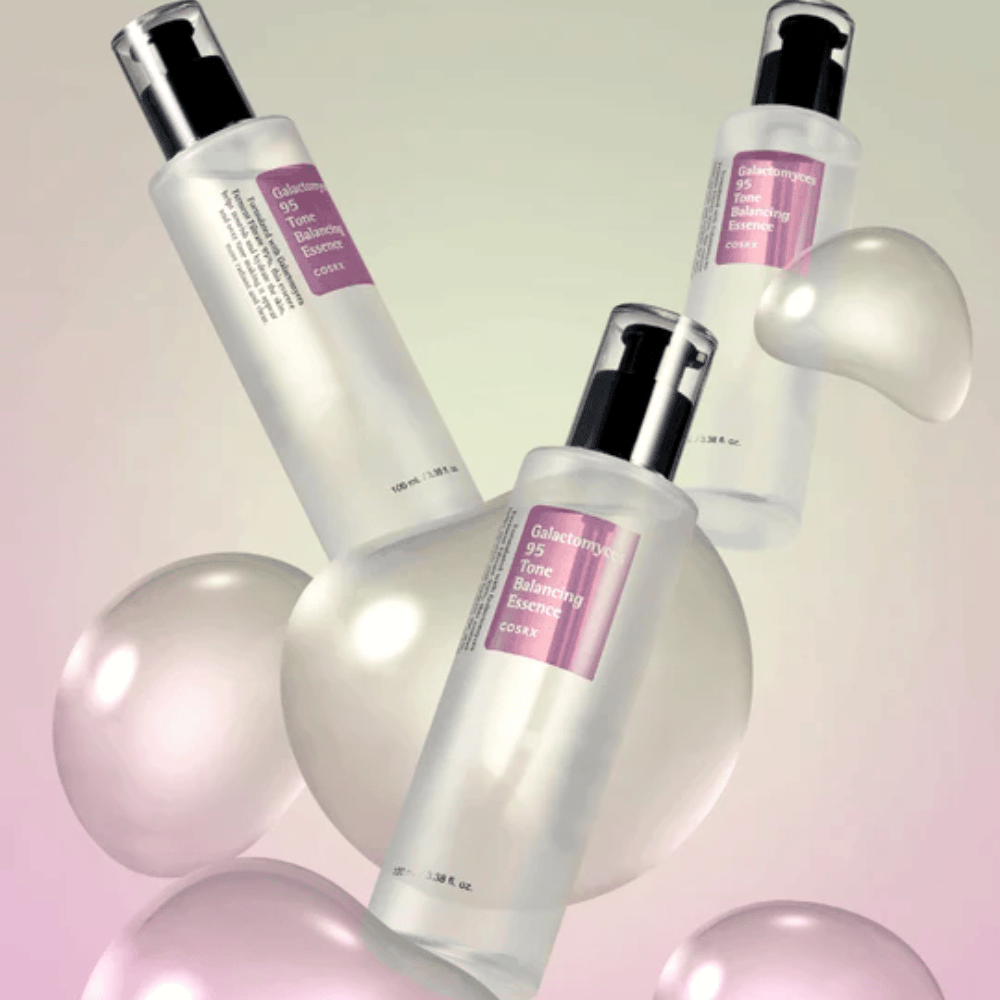 Tre flaskor av COSRX Galactomyces 95 Tone Balancing Essence omgivna av ljusa bubblor. Hudförbättrande essens som jämnar ut hudton och ger naturlig glans.