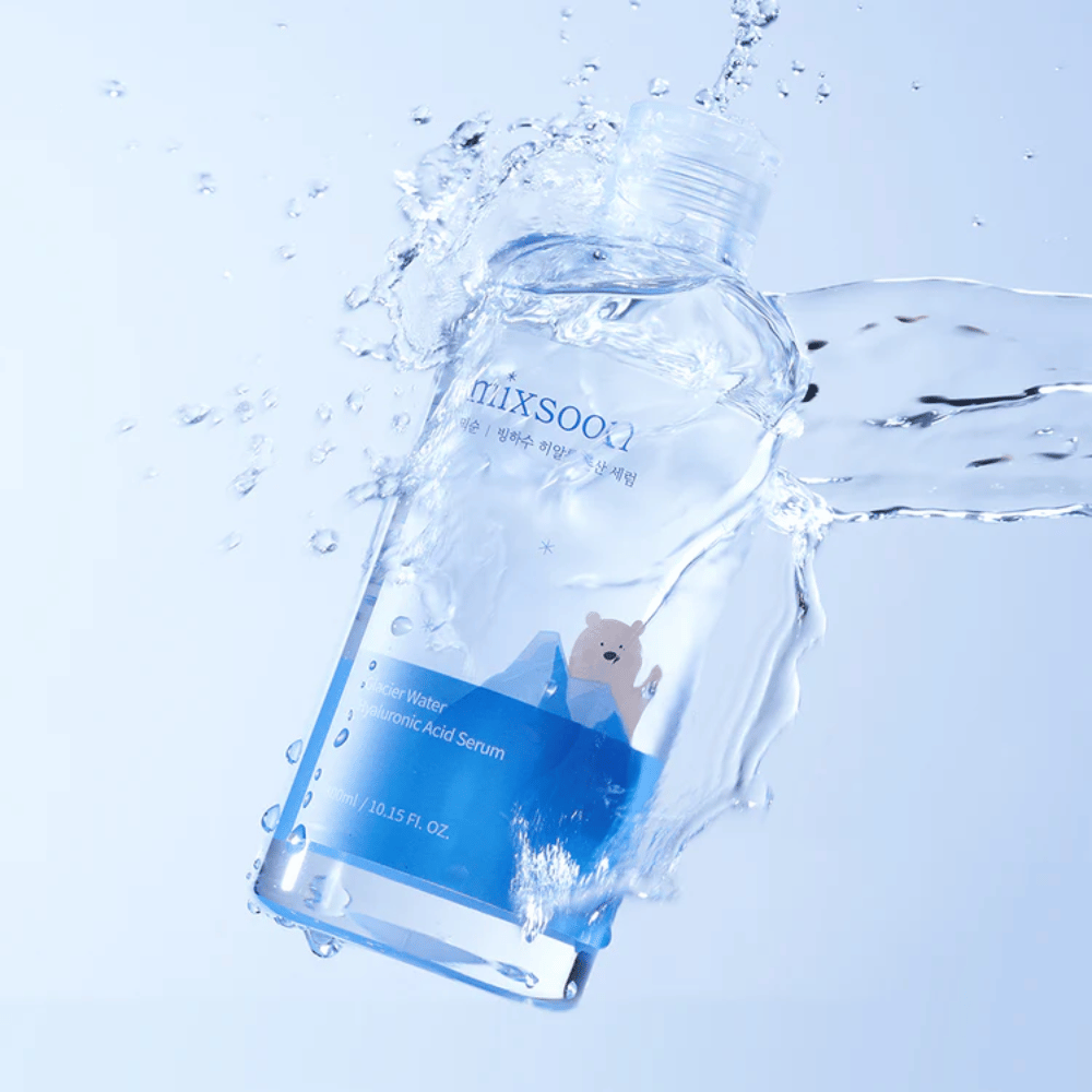 Mixsoon Glacier Water Hyaluronic Acid Serum-butelka z niebieską etykietą i motywem niedźwiedzia polarnego otoczona rozpryskującą się wodą na jasnoniebieskim tle.