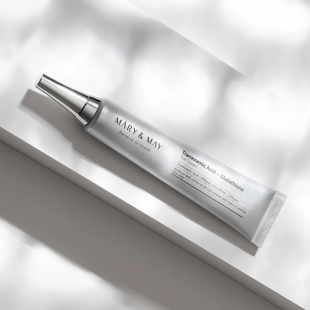 Zbliżenie na Mary&May Tranexamic Acid + Glutathione Eye Cream z metalowym aplikatorem, opracowany w celu rozjaśnienia ciemnych kręgów i wyrównania kolorytu skóry wokół oczu.