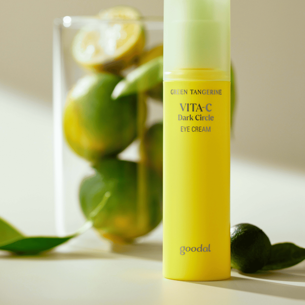 Butelka Goodal Green Tangerine Vita C Dark Circle Eye Cream 30ml na stole obok limonki.